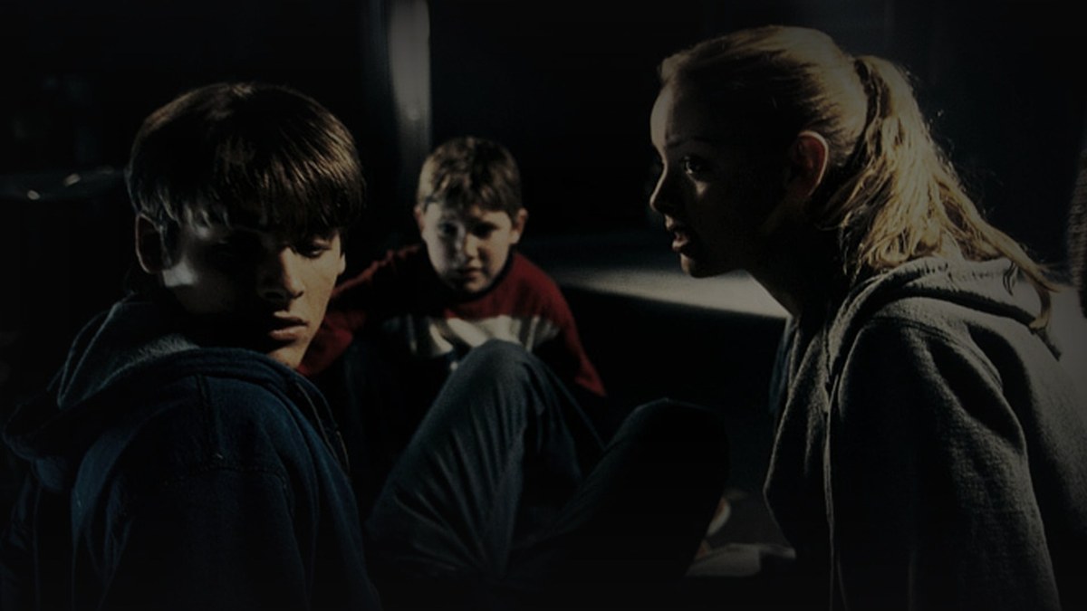 Still from Fear of the Dark (2003) — 16:9 still sourced from thetvdb.com (backgrounds/31108), discovered via yandex images search. letterboxd only had a portrait poster for this film (no 16:9 still exists there), so the skill's ddg-images / yandex-images fallback path was used. baked through scripts/bake_dark_photo.py at default factor, mean brightness 16.4 (appropriate for a horror film with a dim source still).