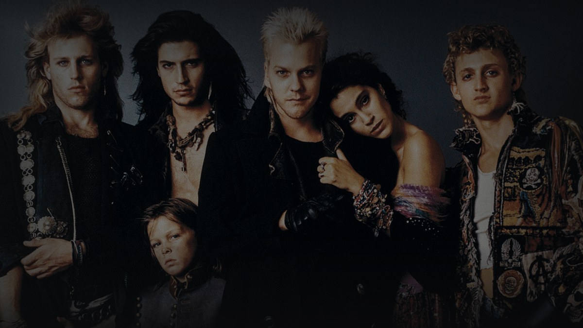 Still from The Lost Boys (1987) — 16:9 still from Letterboxd (the 1200x675 crop variant), baked through scripts/bake_dark_photo.py at default factor, mean brightness to be verified after bake. source: the lost boys gang, the canonical still for the film.