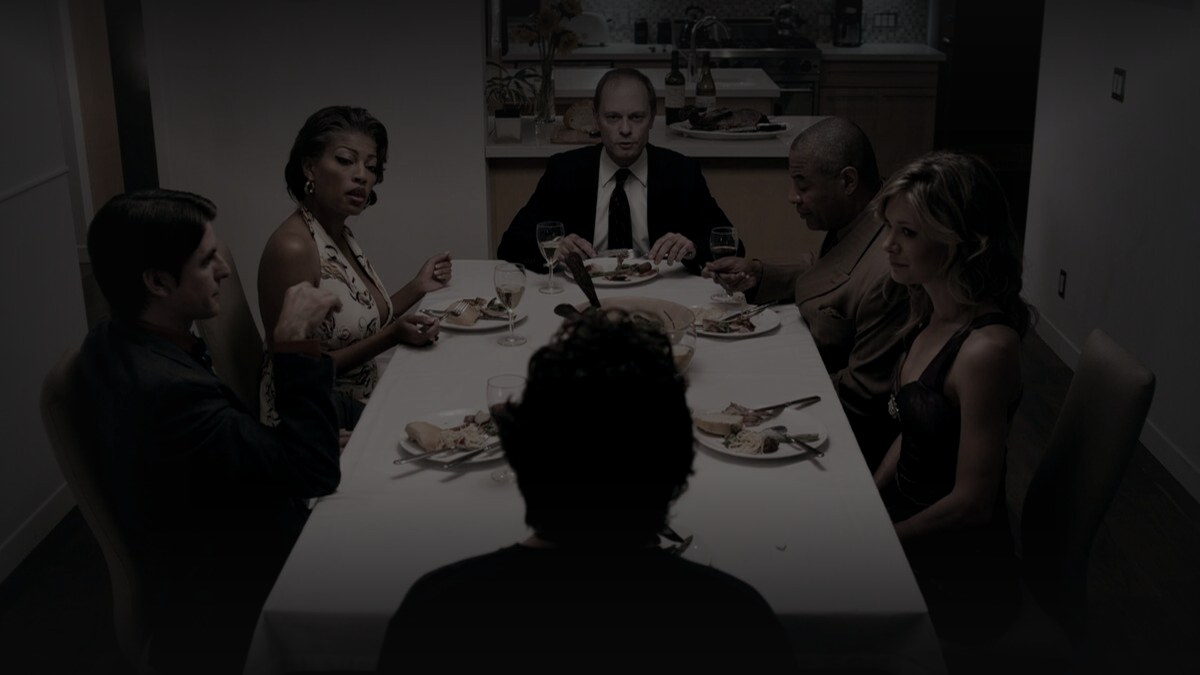 Still from The Perfect Host (2010) — 16:9 still from Letterboxd (the 1200x675 crop variant), baked through scripts/bake_dark_photo.py at default factor, mean brightness to be verified after bake. source: david hyde pierce as warwick wilson, the canonical still for the film.